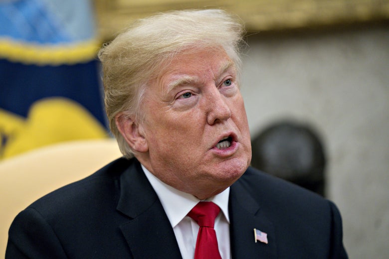 Trump opens his mouth to speak while seated in the Oval Office.